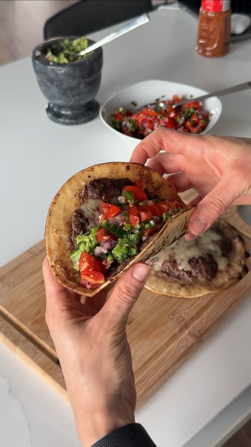 Smash Burger Tacos (36g protein per two tacos)

This recipe has a HOLD on Michael and I 😭

The below recipe makes two tacos:

Guacamole:
- 1 avocado (mashed)
- 1 jalapẽno (finely diced)
- 1/4 red onion (finely diced)
- 1 tsp tajin
- Juice from 1/4 lime

Tomato Salsa:
- Handful of cherry tomatoes (diced)
- 1 jalapẽno (finely diced)
- 1/4 red onion (finely diced)
- 1 tsp salt
- Juice from 1/4 lime

“Big Mac” Sauce:
- 1/4 cup plain greek yogurt (Siggis Skyr would be best)
- 1-2 tsp sriracha
- 1-1.5 tsp dijon mustard
- 1-2 tbsp of pickle juice
- 1 tsp salt
- Optional: add chopped up pickles

Smash Taco:
On two small tortillas, spread 150g (total) of lean ground beef in a thin layer, covering the entirety of each tortilla. Sprinkle with salt on top.

On medium high heat, let your pan heat up for 1min. Add your tortilla face down (ground beef side down) and press down on it with a spatula, applying pressure to each side to make sure the ground beef doesn’t separate from the tortilla. After 1-2mins, flip the tortilla and let the back side cook in the ground beef oil for 1-2mins. Flip the tortilla onto the ground beef side once more, really applying pressure to the sides to make sure the fat of the ground beef gets cooked. After another 1-2mins, flip the tortilla once more and make sure the beef looks cooked all the way through. Add mozzarella cheese on top and cover with a lid for 30sec to let the cheese melt. Once melted, remove the tortilla from the heat and let it rest for 5mins.

Plating: On top of your two tortillas, add your guacamole and tomato salsa. Serve with a dollop of “Big Mac” sauce.