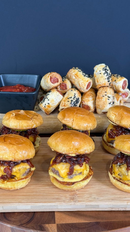 Serving up the ultimate Footy Finals Feast with the Coles BBQ Entertaining range 2 for $15 offer. 🍔 🏉 T&C’s apply.

Ingredients:

Kransky Sausage Rolls:
* 1 pack Coles Pork Kransky Bites with Mozzarella * Puff pastry sheets * 1 egg * Splash of milk * Black sesame seeds * Coles Tomato Chutney

Beef Sliders:
* 1 pack Coles Beef Slider Patties * Brioche Slider buns * Burger cheese slices * Coles burger sauce * Pickles, sliced

Bacon Jam:
* 6 slices middle bacon, diced * 2 red onions, thinly sliced * 1 tbsp butter * 3 tbsp brown sugar * 2 tbsp balsamic vinegar * 2 tsp Worcestershire sauce * 1 tsp sweet paprika

Method:

Start by making the bacon jam. Place diced bacon into a cold pan, turn the heat to medium-low. Cook for 8–10 minutes until the fat has rendered and the bacon is lightly crispy. 

Remove the bacon and discard most of the fat, leaving a little in the pan.

Add butter & sliced red onions to the pan. Cook on low heat until the onions are soft and starting to caramelise. Add a splash of water to deglaze the pan and loosen any stuck bits.

Return the bacon to the pan. Add brown sugar, vinegar, Worcestershire sauce, and paprika. Stir well and simmer on low for 15–20 minutes, or until thick and jammy.

Preheat your oven to 180°C.

Crack the egg into a small bowl whisk with milk to make an egg wash.

Lay three kransky bites horizontally along one edge of each puff pastry sheet. Roll the pastry over tightly to encase the kranskys and seal the edge with some egg wash.

Slice the rolled pastry into smaller sausage rolls and place them seam-side down on a baking tray lined with baking paper. Brush tops with egg wash and sprinkle with black sesame.

Bake for about 20 minutes, or until golden and puffed. Serve with tomato chutney or mustard.

While the sausage rolls are baking, heat a clean pan with a little oil, cook the beef slider patties according per packet instructions.

When nearly cooked, top each patty with a slice of cheese and melt it under a grill.

Toast the slider buns. Spread burger sauce on the buns, then add the patty, a spoonful of bacon jam and a pickle slice. Place the top bun on and serve.
Enjoy!

#coles AD @colessupermarkets