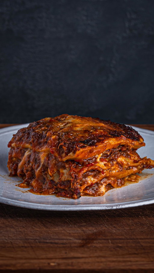 The longer version with ragu & pasta process.

Recipe

1 Thor’s hammer beef shin joint (I used a 4kg joint)
20g Mediterranean rub
250g beef stock

1. cut away any excess fat and sinew from the beef, tying up the joint with butcher’s twine so it holds its shape.
2. Render down the fat you just cut off and brush that tallow on to the joint. Follow that up with a good covering of the rub you’re using. I do all this in a baking tray which I’ll also smoke the joint in.
3. Smoke at 225°F (107°C) until it hits 170°F (76°C) internal. This will take around 4 to 5 hours.
4. Pour the beef stock into the baking tray and cover the whole thing with foil. Continue to cook in the smoker/grill or transfer to the oven at the same temperature until it hits 205°F (96°C).
5. Open up the foil to allow the steam to escape then loosely close and allow to rest for 1 hour.

Smoked Beef Shin Ragu

700g smoked beef shin
800g tinned tomatoes
250g passata 
250g beef stock
185g tomato Paste
2 medium carrots
3 stalk celery
1 large onion
3/4 bottle Chianti red wine
Extra Virgin Olive Oil
Salt
Corn Starch (Optional)
Rosemary
Sage
Black Pepper
Bay Leaf

1. Chop or mince your vegetables for the sofrito and put to one side.
2. Bring a heavy bottom pan to a medium heat and cover the base with olive oil.
3. Add the sofrito and cook until most of the moisture is sweated off. Add in the tomato paste and cook until it starts to stick to the bottom of the pan a little.
4. Go in with the red wine and reduce down by half and add in the meat, crushed tomatoes, passata, beef stock, and a boquet garni of all the fresh herbs.
5. Cook until it’s reduced to a thickness you want for the lasagna. Personally I like it to be very thick to avoid a watery lasagne.

Bechamel Sauce

1l milk
100g unsalted Butter
100g plain flour
Salt
Fresh Nutmeg
White Pepper

Lasagne Sheets

300g 00 flour
3 eggs
1 yolk

500g 00 flour
5 eggs

Assembly

Lasagne Sheets
4 layers
Make sure there’s no pasta sheet showing at the top that would otherwise dry up when cooking.
165°C for 40 minutes to allow the pasta to absorb the ragu and bechamel. First 20 mins is covered with tin foil.
Cover with a cloth and let it rest for up to 10 minutes.