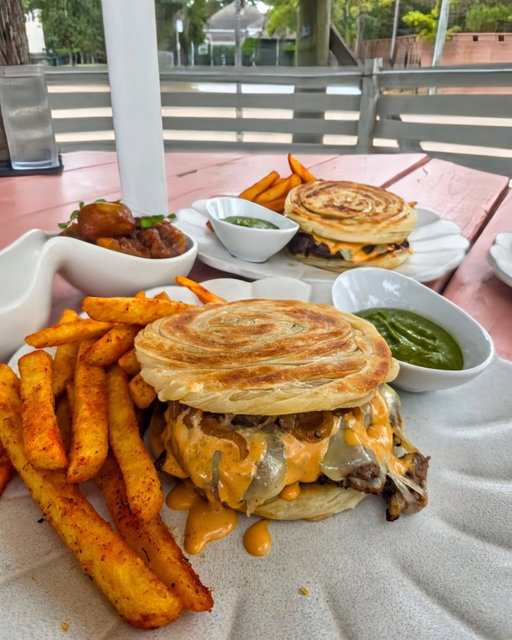 🍔 As the star of Kitchen Rumors' new all-day happy hour, executive chef Jassi Bindra has debuted a Paratha Smash Burger featuring two smashed Texas Wagyu patties layered with melted cheese, caramelized grilled onions and smashburger sauce. The beef is enveloped in a golden, flaky paratha, its buttery, layered texture offering a rich counterpoint to the charred, juicy edges of the patties.

🍟 Each order is accompanied by @KahaniSocialGroup signature Balle Balle Fries, dusted with Indian spices and served with Naughty Sauce — a creamy, spiced, cilantro and avocado-based sauce, adding a fresh, vibrant kick to every bite. 🌿 The launch exemplifies the group’s inventive, globally inspired approach to flavor.

🆕️ It's available starting Sunday, October 19 as part of the restaurant's all-day happy hour, which is now offered Sundays through Thursdays (closed on Mondays) at the bar and on the patio.

🍸 The menu also features five cocktails priced at $8, discounted wines, beer and other small bites such as Pok Pok Po Chicken Sliders ($9), Crispy Kale with wasabi white peas, onion, tomato, tamarind and mint chutney ($8), Sichuan Eggplant and more. 

🔥 We genuinely loved every bite and sip we got to sample. The flavors are big, tantalizing and layered and the prices are thusly kind of unbelievable. I highly recommend it for your next happy hour destination.

📍 @KitchenRumorsHTX 2310 Decatur
📝 @MadmanMario