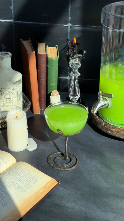 Avada Kedavra Mock-Tini 🐍 
(batched recipe) 

I don’t care how old I get, I will re-watch the Harry Potter Series 2x a year — at a minimum. Who’s with me?! 

𝐰𝐡𝐚𝐭 𝐲𝐨𝐮’𝐥𝐥 𝐧𝐞𝐞𝐝: ⁣
• 2 cups of NA tequila (or dealers choice) 
• 2 cups of pineapple juice 
• 1 cup of fresh lime juice 
• 1 cup of NA orange sec 
• 3 cups of NA absinthe
• Optional: 2 cups of filtered water, to dilute
• A few tsp of edible glitter 
• Ice
• Serving: 4 oz of above batched mocktail, topped with ginger beer. 
⁣
𝐨𝐭𝐡𝐞𝐫 𝐩𝐨𝐬𝐭 𝐝𝐞𝐭𝐚𝐢𝐥𝐬: 
• Vintage books: fb marketplace 
• Drink dispenser: @crateandbarrel 
• Wooden riser: @madeforhomehh 
• Black candles: @partycity 
• Vintage glass candlesticks + silver tray: @etsy 
• Brass skull: @target 
• Dusty bottles: DIY! The process — a recycled @drinkspiritless bottle, printed out free spooky labels, dyed them with green tea bags, spritzed the bottle with @rizoscurls hair spray, and dusted it with a clay mask. 😭👏🏽

Cheers 🪄
—————————
#harrypotter #avadakedavra #slytherin #halloweencocktails #spookyseason #spooktober #batchedcocktails #hp #mocktail #mocktailrecipe #zeroproof #soberoctober