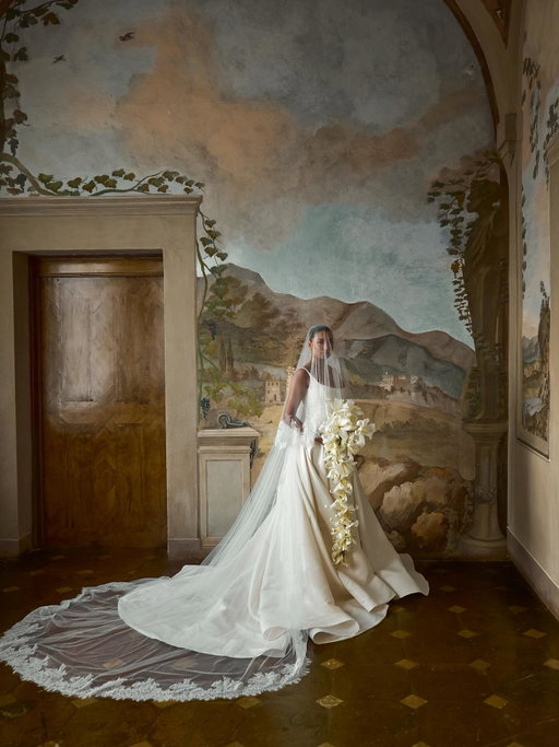 I tried on so many dresses before finding the one. Each was beautiful in its own way, but none of them felt quite like me. At one of my last fittings (six months before the wedding) I tried on Gown No.18 by Sept New York and immediately knew it was the one. It was the first dress that felt like me, timeless in silhouette, yet modern in the way it moved.

I added buttons to the back of the drop waist and styled it with my dream French lace veil. To switch it up for the dinner, I swapped the veil for a long tulle scarf by Sept, I love how it transformed the look, adding a softer, more contemporary touch while keeping the same sense of ease and refinement.

Wedding planner @morettievents 
Photographer @theferros 
Content creator @silvi_lubilubi 
Makeup: @danielaxalves 
Dress @septnewyork 
Trieu’s suit & shoes @tomford 
Flowers @biancospinoflowers 
Venue @cetinale