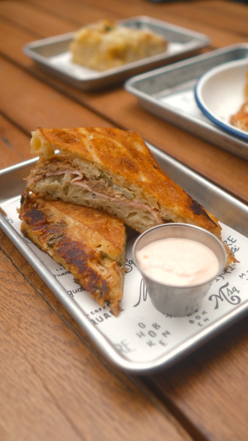 Cubano: Five-Hour Braised Citrus-Garlic Mojo Pork, Smoked Ham, Swiss Cheese, House Pickles, and Cuban Dijon, Pressed on our Focaccia, Served with Smoked Guava Aioli for Dipping.