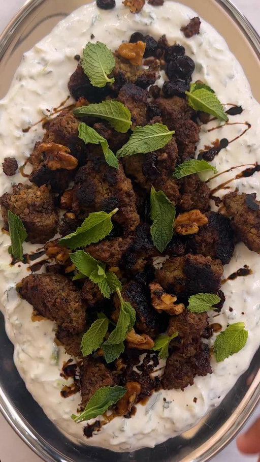 Here’s how to make @zaynab_issa’s Smashed Beef Kebab With Cucumber Yogurt:

• 2 cups full-fat or low-fat Greek yogurt (about 16 ounces)
• 2 mini cucumbers (about ½ pound), grated on the large holes of a box grater
• 3 tablespoons finely chopped mint, plus mint leaves for serving
• 1 large garlic clove, finely grated
• 1 pound ground beef (preferably 80% lean) or ground lamb
• 1 small yellow onion, grated on the large holes of a box grater (see Tip)
• ½ teaspoon ground turmeric
• 2 teaspoons kosher salt (such as Diamond Crystal)
• Freshly ground black pepper
• ¼ cup walnut halves or pieces, or both (see Tip)
• 2 tablespoons raisins or dried cranberries
• Pomegranate molasses, optional, for serving
• Warmed pita or white rice, for serving

Add the yogurt, cucumbers, chopped mint and garlic to a medium bowl. Mix well to combine. Chill until ready to serve.

Add the beef, onion, turmeric, 1 teaspoon of salt and lots of black pepper to a second medium bowl and mix well to combine.

Heat a large well-seasoned cast-iron skillet (or other large heavy-bottomed pan) over medium-high. Once the skillet is very hot, divide beef into large, irregular chunks by using two spoons or your hands and drop into the skillet. Cook, undisturbed, until charred and crisp on the underside and browned at least halfway up the sides, 6 to 8 minutes.

Using a wooden spoon, toss the meat, breaking up any very large pieces. Add the walnuts and raisins and continue to cook, stirring often, until the meat is cooked to desired doneness and the walnuts are toasted, 2 to 3 minutes more.

Remove the yogurt from the fridge and season with the remaining 1 teaspoon of salt. Spread the yogurt on the bottom of a serving platter and top with the crispy meat. Finish with a drizzle of pomegranate molasses, if using, and garnish with mint leaves. Serve with warmed pita or rice.

Tips:
To minimize eye irritation while grating, use a chilled onion.
Two tablespoons of pistachios or pine nuts can be substituted for the walnuts.