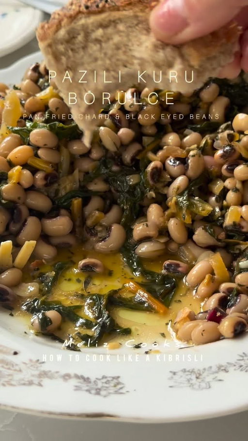 How to cook like a Kıbrıslı: Melek Nene’s Pazılı Kuru Börülce (Pan Fried Chard & Black Eyed Beans) Meliz’s Kitchen 🫘 🧅 🧄🌿🍋🫒 
Serves 6–8
450g cooked black eyed beans* (see notes pinned comment) 
200 g (7 oz) Swiss chard roughly chopped (stems removed, finely chopped and kept to one side) or the same quantity of spinach
3 tbsp olive oil
1 large onion, peeled and finely diced
1/2 tsp sea salt flakes 
4 garlic cloves, finely sliced

For the dressing
4 tbsp extra virgin olive oil, plus extra to serve
4 tbsp lemon juice
1 tsp sea salt flakes
1 tsp dried mint

METHOD: 

If using dried black eyed beans, spread them out evenly on a large tray and remove and discard any stones or broken beans. Soak and cook as per the instructions below. You can check that they’re cooked by squeezing one of the cooked beans in between your thumb and
forefinger. Once cooked, remove pan from heat, drain the beans in a colander. You cook prepare these the night before too but I love using them when they’re still warm from being freshly cooked as the beans soak up the flavour and juices of the remaining ingredients better this way. 

Wash the chard thoroughly to remove any dirt or grit before roughly chopping the leaves.
In a frying pan, heat olive oil, add onion, along with 1/2 tsp sea sally flakes, soften over a low heat for 12–15 minutes until translucent. Add the finely chopped chard stalks and cook for a few minutes more. Once softened, increase the heat a little so the onions and chard stalks start to caramelise, then add the garlic, turn the heat down again and cook for another 2 minutes. Add the chopped chard leaves to the pan, reduce the heat and cook until the greens have wilted. Remove the pan from the heat, add the drain beans to the pan and stir well until the beans are fully coated in the greens, onions and garlic.

Transfer the mixture to a serving dish.
Drizzle and sprinkle over all of the dressing ingredients, stir well and serve with an extra drizzle of extra virgin olive oil. It’s the perfect accompaniment to Badadez Köftesi (coming soon) and fresh or canned fish such as tuna or smoked mackerel, chips, bread and a fresh salad.

#melizcooks #beans #salad