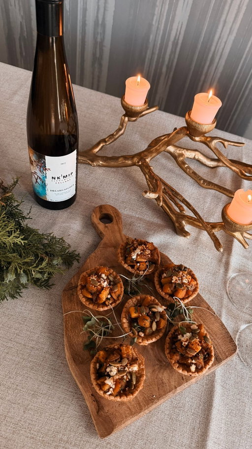 Squash is one of the Three Sisters grown together for generations, rooted in Indigenous knowledge, and essential to seasonal harvest.
⠀
This final recipe in our 𝑮𝒂𝒕𝒉𝒆𝒓 series honours that legacy.
⠀
Harvest Tarts — roasted butternut squash and red onion, warm spices, creamy goat cheese, and a crunch of pepitas, all nestled in golden tart shells.
⠀
Developed by Nk’Mip Cellars Winemaker Justin Hall and Chef Sean from Sweetgrass Kitchen, this recipe brings together land-based knowledge, tradition, and simplicity in every bite.
⠀
✨ Best paired with Dreamcatcher, bright, fruit-forward, and a perfect contrast to the richness of roasted squash.

A final toast to the season and to the land that continues to feed us.

🥧  Harvest Tarts
Ingredients:
• 12 mini tart shells (phyllo or pastry)
• 1 cup peeled, diced butternut squash
• ½ small red onion, finely diced
• 1 tbsp olive oil
• ¼ tsp cinnamon
• Salt and pepper to taste
• ¼ cup goat cheese, crumbled
• Toasted pumpkin seeds (pepitas) for garnish

Instructions:
Toss squash and onion with oil, cinnamon, salt + pepper.
Roast at 400°F for 20–25 minutes until soft + golden.
Lightly mash (or leave chunky).
Fill each tart shell with the squash hash.
Top with goat cheese + pepitas. Serve warm or at room temp.

This is how we honour the harvest — with food that nourishes, and moments that bring us back to each other.

Three Sisters squash recipe, Gather recipe series, Indigenous harvest food, Dreamcatcher wine pairing, goat cheese tartlets, BC wine and food, Nk’Mip Cellars holiday recipes