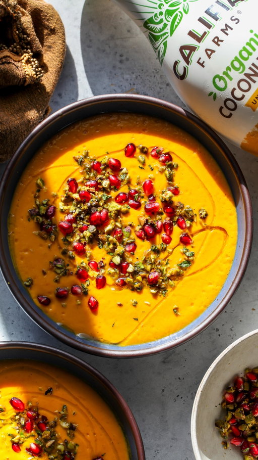 The coziest Golden Butternut Ginger-Coconut Soup (FULL recipe below) topped with a vibrant pomegranate gremolata. Naturally dairy-free (but with a sneaky protein boost) and the silkiest broth from @califiafarms Organic Coconutmilk. #califiapartner 

Golden Butternut Coconut Soup
SERVES 4

1 (2 – 2 ½ lb.) butternut squash
3 Tbsp. extra-virgin olive oil
1 tsp. ground turmeric
1 tsp. ground ginger
1 tsp. paprika
1 tsp. kosher salt + ½ tsp. black pepper
1 red bell pepper, cored and sliced into quarters
1 yellow onion, peeled and sliced into large segments
4 garlic cloves (peel on)
1 (15-16 oz.) block silken tofu, drained
2 cups vegetable broth
½ cup Califia Farms Organic Coconutmilk
1 Tbsp. fresh lemon juice
1/3 cup pomegranate arils
¼ cup roasted, salted pistachios, finely chopped
1 Tbsp. chopped fresh mint leaves
1 tsp. lemon zest
 
1. Preheat oven to 400ºF. Slice butternut squash in half lengthwise and scoop out seeds. Score the flesh in a crosshatch design and arrange on a large rimmed baking sheet or 9x13-inch baking pan. Arrange bell pepper and onion segments around squash and drizzle everything with olive oil. Mix spices (turmeric, ginger, paprika, salt, and pepper) in a small bowl and sprinkle evenly over vegetables. Turn butternut squash so it’s cut-side down. Place garlic cloves in a small piece of foil or parchment paper and lightly drizzle with olive oil. Wrap loosely and place in baking pan. Transfer pan to the oven and roast until the squash is fork-tender, about 60 minutes.
2. Meanwhile, prepare Pomegranate Gremolata by combining pomegranate arils, pistachios, mint, & lemon zest in a small bowl.
3. Once the veggies are almost done roasting, combine broth and coconutmilk in a small saucepan and bring to a gentle simmer.
4. Scoop out the flesh of the roasted butternut squash and transfer it a blender. Add roasted bell pepper and onion segments, along with garlic (removed from skin), silken tofu, and warm broth mixture. Blend on high speed until smooth and creamy. Add 1 Tbsp. of fresh lemon juice; stir to combine. Taste and adjust seasonings as needed. Pour soup into bowls and garnish with Pomegranate Gremolata and a drizzle of olive oil, if desired.