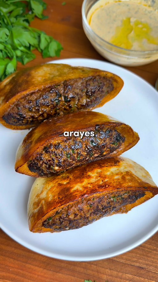 Top 3 Recipes of 2025: Arayes🔥

Since all of you are asking - the app link for Osta is in my bio or you can search “Osta Recipes” on the App Store or Google Play store ‼️🫶

Crispy, Juicy Middle Eastern Meat-Stuffed Pitas with a Garlic Tahini Sauce 🥙

Comment “Recipe” and I’ll send you the full recipe card for free!!

Ingredients:
-4 small pitas, cut in half
-1 yellow onion, grated & squeezed dry
-7 garlic cloves, minced
-2 tbsp tomato paste
-1/3 cup fresh parsley, chopped
-1/3 cup fresh cilantro, chopped (optional but excellent)
-1 tbsp olive oil
-1 lb (0.45 kg) lean ground beef
-Spices: 1 tsp salt, 1 tsp black pepper, 1 tsp cinnamon, 2 tsp cumin, 2 tsp paprika, 1 tsp allspice

For the Garlic Tahini Sauce:
-1/2 cup Greek yogurt
-3 tbsp tahini
-1/2 lemon, juiced
-2 garlic cloves, minced
-2 tbsp olive oil
-1/4 cup fresh parsley, chopped
-1/4 cup fresh cilantro, chopped
-1 tsp each: cumin, salt, pepper, paprika

Instructions:
1. Preheat your oven to 350°F (175°C). Grate your onion and squeeze every last drop of liquid out using paper towel or cheesecloth. 
2. In a large bowl, combine the ground beef, tomato paste, minced garlic, all the spices, parsley, cilantro (if using), and that very dry grated onion. Mix with your hands for about 2 minutes.
3. Cut each pita in half. If they don’t already have a pocket, carefully use a knife to make one. Now, pack them with your beef mixture — and I mean stuff them. You want them full but not bursting (ripped pita = heartbreak).
4. Crisp ’Em Up: Brush the outsides of the stuffed pitas lightly with olive oil. Heat a lightly oiled skillet over medium heat. Place each arayes meat-side down and sear for 1–2 minutes until you get that gorgeous crust. Then sear the pita sides until golden and crisp. 
5. Transfer the seared arayes to a baking sheet and finish them in the oven for 10–15 minutes, until fully cooked through. 
6. While they bake, whisk together all the garlic tahini sauce ingredients in a bowl. Taste and adjust lemon, salt, or garlic levels to your liking.
7. When the arayes are hot out of the oven, optionally brush them with melted garlic herb butter. Enjoy! 🫡