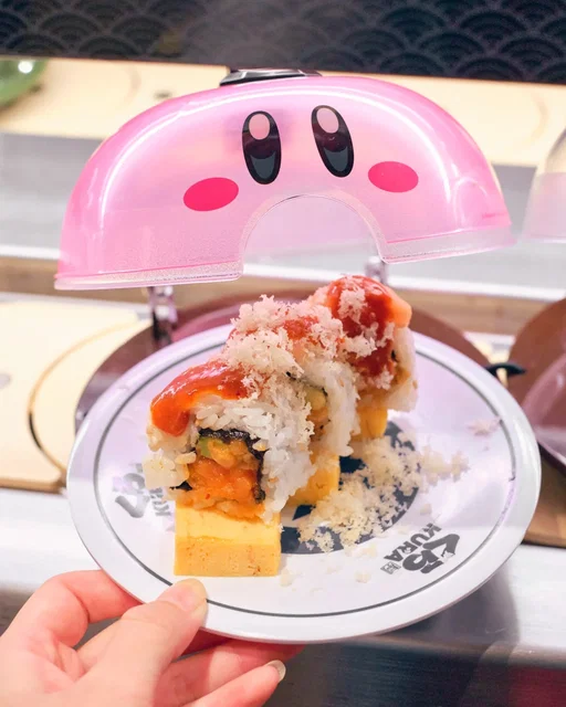 Kirby x Kura Sushi collaboration is on until January 31, 2026! I couldn't miss this cute collab seeing the kawaii Kirby dome on the revolving belt. 🥹

There are 2 special rolls: Kirby dreamy crunchy roll and Waddle Dee feisty feast roll. Decorated with pink and orange sauces respectfully for the little guys. The tamago egg on the bottom represents them riding Warp Stars. ⭐

Since I'm a nigiri girlie, they were a little too saucy for me, but I still enjoyed experiencing this collab! There is Kirby themed decor around the restaurant and gachapon prizes to win as well!

📍 Kura Sushi USA @kurasushi_usa 

sushi rolls Nintendo #videogamefood gamers #gamer4life #gamergirls #kirbyfanart #themedfood bikkura pon