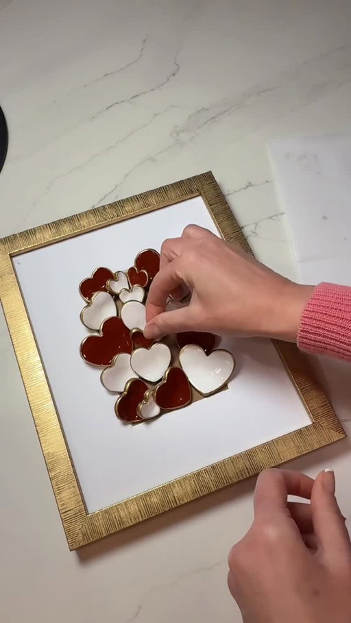 Started with air-dry crayola clay, heart shaped cookie cutters, letting them dry on a paper plate to create the perfect curved shape. I painted them crimson and white with acrylic paint, added gold pin trim on the smooth edges for extra pop and pizzazz, then removed the glass from a budget frame and glued the hearts directly onto the mat for a fun 3D pop-out effect. I love putting a creative spin on DIY crafts, turning simple supplies into personalized home decor and a work of art with lots of beauty and character. #art #valentines #handmade #artist #décor