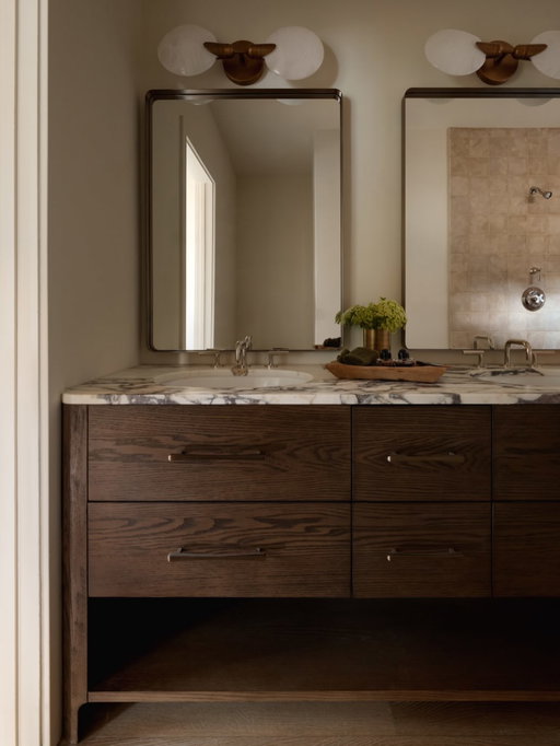 Modern in feeling, timeless in execution—this bathroom by @lindseycolhoundesign introduces subtle drama through material movement, gentle curves, and depth of tone.