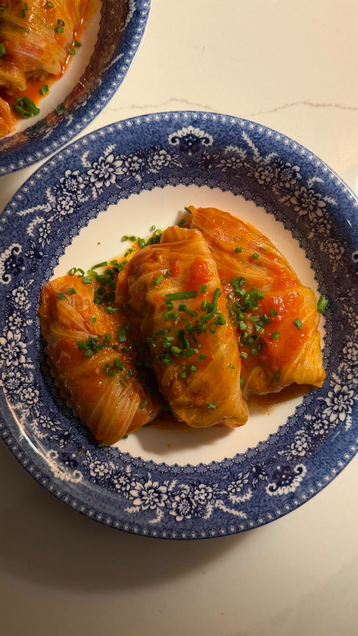 (Recipe below) Cozy week day evening at home making stuffed cabbages

Stuffed Cabbage Rolls
Makes 10–12 rolls

Ingredients
* 1 whole green cabbage
* 452 g (1 lb) Beyond Meat (or any vegan ground you love)
* 1½ cups cooked white rice 
* 1.5 teaspoon garlic powder
* 1.5 teaspoon Paprika
* 1.5 teaspoon dried thyme
* Salt, to taste
* Black pepper, to taste
* 1/4 cup fresh chives, thinly sliced
* 2 cups tomato sauce of choice
* 2 cups water

Instructions
1. Bring a large pot of salted water to a boil. Carefully add the whole cabbage and boil until the outer leaves are tender and easy to peel away, about 8–10 minutes. Remove the cabbage from the pot, let it cool slightly, then gently pull apart the leaves. Lay them flat on a paper towel and let them rest while you prepare the filling.
2. In a large bowl, combine the vegan ground, cooked rice, garlic powder, paprika, salt, pepper, dried thyme, and 3/4 of the chives. Mix gently until just combined,don’t overwork it.
3. Place a cabbage leaf on a flat surface. Spoon about 2 tablespoons of the filling near the edge of the leaf. Fold in the sides and roll it up snugly, burrito-style, tucking as you go. Repeat until all the filling is used.
4. Arrange the cabbage rolls seam-side down in a wide pan or shallow pot. Turn the heat to medium-high and cook for about 2 minutes, just until the cabbage lightly goldens and seals.
5. Lower the heat to a gentle simmer. Pour in the tomato sauce and water, there should be enough liquid to mostly cover the rolls. Cover and let simmer for 40 minutes, allowing the flavors to meld and the rolls to become tender.
6. Spoon the rolls into bowls with plenty of sauce, and finish with extra sliced chives on top.

Inspired by my friend @reserve_home 

#minivlog #homevlog