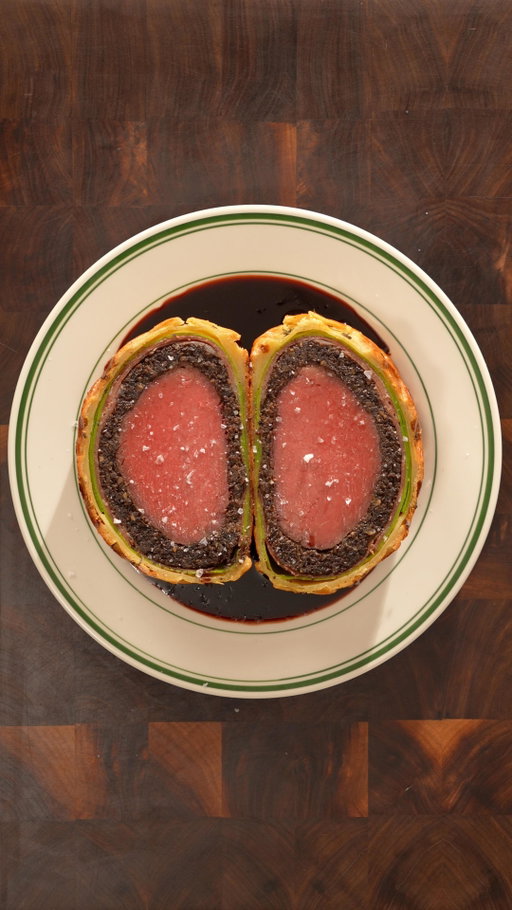 Oh no not a Beef Wellington recipe 😩

Ingredients

Beef:
- Center-cut beef tenderloin 900g
- Salt
- Frying oil (I used beef fat)
- Dijon Mustard
- Prosciutto

Mushroom Duxelle:
- Cremini mushrooms 600g
- Salt
- Shallots 150g
- Garlic 3 cloves
- Herbs: oregano, thyme, rosemary
- Madeira 1/3cup (can substitute with beef stock)

Spinach Crepes:
- Spinach 1 cup packed
- 2 eggs
- Milk 1/2 cup
- Melted butter 1 TBSP
- Salt 1 tsp
- AP flour 1/2 cup

Assembly:
- Puff pastry 2 sheets
- Egg wash (2 eggs + 1 TBSP milk)
- Thyme

Wine Sauce:
- Red wine 500ml
- Beef stock 500ml
- Butter 1.5 TBSP

Instructions

Beef:
- Season the meat with salt and cook it in the oven at 200F for 65 minutes until the internal temperature is 122F.
- Shallow fry the meat at 375F for 15 seconds on each side before brushing with dijon mustard.

Mushroom Duxelle:
- Cook chopped mushrooms on low heat with salt, chopped shallots, chopped garlic, butter and herbs for about 1 hour before deglazing with madeira.

Spinach Crepes:
- Blanch spinach in boiling water for 15 seconds before cooling in ice water and patting dry.
- Blend the spinach with eggs, milk, melted butter, AP flour and salt. Let the batter rest for 30 minutes and strain.
- Cook the batter on a pan with butter.

Assembly:
- Lay prosciutto on the crepes before spreading a bed of mushroom duxelle.
- Use saran wrap to tighly roll the meat inside of the crepes into a cylinder and refrigerate for at least 1 hour.
- Cover the wrapped meat with puff pastry and completely freeze the beef wellington.
- Bake at 450F for 35 minutes until the puff pastry is golden and then at 150F for another 45 minutes until the center of the wellington is at 110F.

Wine Sauce:
- Reduce red with beef stock until it halves and emulsify with butter at the end.
