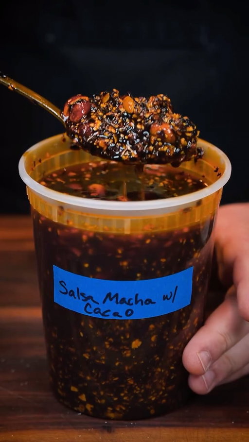 salsa macha with cacao this week! made this custom for my bro @wade____hall. the smokey chipotle and cacao are a match made in heaven 🔥 recipe below 👇🏽 #salsa101 

SALSA MACHA
YIELD: 1 QUART

565g olive oil
75g red-skinned peanuts, raw
75g pumpkin seeds, raw
75g peeled garlic, whole
45g ancho chiles, seeded/stemmed/cut into small pieces
25g guajillo chiles, seeded/stemmed/cut into small pieces
12g chipotle chiles, seeded/stemmed/cut into small pieces
5g chiles de arbol, stemmed
20g sesame seeds, raw
15g cacao nibs
2g Mexican oregano, dried
1g coriander seeds, whole
10g apple cider vinegar powder or 30g apple cider vinegar
15g Diamond Crystal kosher salt
15g sugar

In an appropriately sized pot, combine the oil and the peanuts and heat over medium heat while stirring. Allot peanuts to fry until golden brown. Remove from the oil immediately, and reserve.

Place oil back into the pot, and add the chiles to the oil. Bring chiles up while stirring and cook for a minute or so.  Add the pepitas, sesame seeds, garlic, cacao nibs, and spices into the oil and cook over low heat until the garlic is golden brown and tender. Remove from heat and allow them to cool at room temperature. Once cool, strain the solids from the oil and place in a food processor with the salt, vinegar powder and sugar, grind until your desired texture is reached. Transfer to a storage container, add the oil back in along with the fried peanuts and season to taste. Stir to combine. Allow to marinate for 24 hours, taste and adjust seasoning as needed.