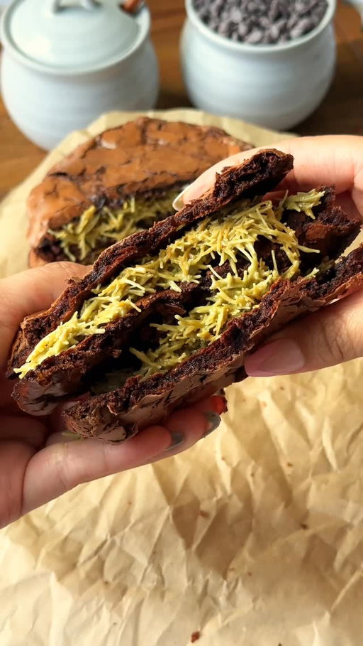 dubai chocolate cookie sandwiches~

chewy brownie cookies stuffed with nutty pistachio kataifi 🤎

for everyone asking, the app link for Osta is in my bio, or you can search “Osta Recipes” in the app store or google play store!

comment “dubai cookie” for a direct link to the recipe!

recipe: 
ingredients:
350g powdered sugar
60–65g cocoa powder (i like 65g) 1/2 tsp salt
3 egg whites from 3 large eggs! (about 1/2 cup of liquid egg whites)
1/2 to 1 cup semi-sweet chocolate chips (optional but recommended!) – depending how much chocolate you like. you can also use milk, but i’m a semi-sweet/dark choco girl.
1 tsp instant coffee
1 tsp vanilla bean paste
3 tbsp pistachio crème

filling:
4 oz crispy kataifi (brown uncooked kataifi in butter until golden)
2 oz pistachio crème (you can totally eyeball this)
30g tahini (again, you can eyeball this)

directions:
in a big bowl, mix together powdered sugar, cocoa powder, salt, egg whites, instant coffee, and vanilla bean paste until you’ve got a thick, glossy batter.
fold in chocolate chips if you’re using them.
swirl in the pistachio crème.
refrigerate the batter for 30–60 minutes.
preheat your oven to 350°f (175°c). line a baking sheet with parchment paper and lightly butter it so the cookies don’t stick.
scoop 2–3 tablespoons of batter per cookie onto the tray. leave at least 4–5 inches between each cookie because they spread a lot. four per sheet is the safest bet, but you can fit six if you don’t mind them touching a little.
bake in the middle of the oven for 8–10 minutes, until crinkly. if you pull them at 8 minutes, they’ll set into a super fudgy texture. if you bake longer, they’ll be less fudgy—10 minutes max but this also depends on your oven. you can tell the cookies are done when the edges are set and the tops are crinkly. 
right after baking, use a round bowl to scoot the edges in so the cookies look nice and round (and fluff up the edges a bit).
transfer off the tray right away so they don’t keep cooking on the hot pan. let them cool completely.
for the filling, mix the crispy kataifi with pistachio crème and tahini until it comes together. spread between two cooled cookies and sandwich it up.
enjoy 🤎
