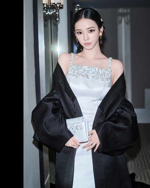 Prada Ambassador Karina ahead of the 2026 Met Gala in New York City. 

Prada Ambassador Karina wore a #Prada white satin dress featuring a tablier neckline embroidered with jet beads and silver crystals, paired with a black satin evening cape, silver leather sandals, Prada Fine Jewelry Couleur Vivante earrings in white gold, peridots, amethysts and diamonds, and a white satin embroidered clutch. 

#PradaPeople #MetGala