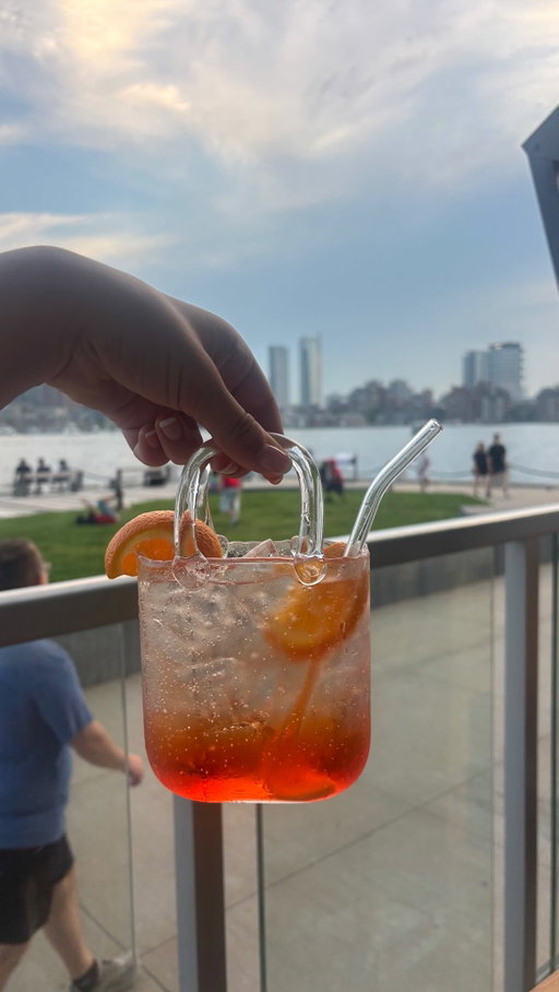 All the details on a sunset spritz in a purse in Boston 👜🍸👇

I am a sucker for a fun presentation, so when I saw this on the menu I knew I needed to do it. It’s a $15 cocktail, but the extra joy felt worth it.

We walked in on a Friday night and ended up having about a 10 minute wait for 2 people on the patio. Luckily, we were just in time for a super vibrant sunset.

We just did drinks and fries so we were super content to take in the view and vibe, but candidly the food here wasn’t my favorite when I went the first time. I’d recommend this more for drinks and apps.

I can say I highly recommend the outdoor seating for the summer atmosphere and our cocktails were yummy!

If you haven’t been to East Boston yet, the water views are insane. It’s easy on the ferry or blue line.

This or Downeast could also be a great spot before attempting Tall Ship 👀

📍La Tavernetta, East Boston (near Maverick T stop)
