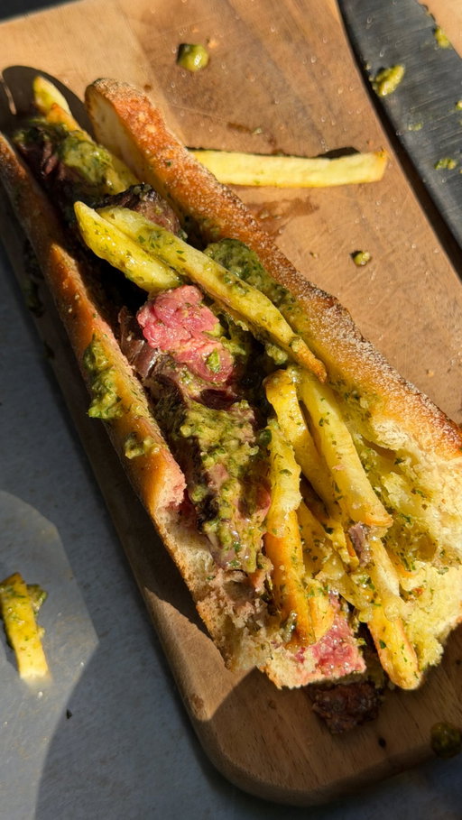 Entrecôte Steak Sandwich Version 2 

After a lot of trial and error this version is the one - it’s the closest thing to that entrecôte steak sandwich I had in Paris. Let me know what you guys think. 

Entrecôte Sauce: 
Shallot, finely sliced
2 tbsp butter
15g walnuts
1 tsp capers (5g)
5 anchovies
1 sprig tarragon (1.5g)
1 bunch chervil
3 sage leaves
5–6 basil leaves
1 bunch parsley
Juice of ½ lemon
1 egg yolk
1 tsp Dijon mustard
1 tbsp Worcestershire sauce
250g unsalted butter
Salt, to taste
Steak 150-200 per sandwich (the original uses Striplion/sirloin/ porterhouse) 
Shoestring fries
Fresh baguette

Method
Soften the shallot in 2 tbsp butter over medium-low heat. Add anchovies, capers and walnuts, cook for 1 minute. Blend with the chopped herbs and lemon juice into a smooth-ish green paste.
Melt the remaining butter. Whisk egg yolk, mustard and Worcestershire together, mix in the herb paste, then slowly drizzle in the melted butter while whisking to emulsify.
Place half the sauce by ina saucepan and bring to simmer until its splits cook out for 2–3 minutes, then whisk it back into the uncooked sauce to re-emulsify. Season with salt and lemon to taste.
Cook the steak to medium, rest, then stir the resting juices through the sauce. Fry the fries until crisp.
Slice open the baguette, slather the base with sauce, layer on sliced steak, more sauce and a pile of fries. Serve.