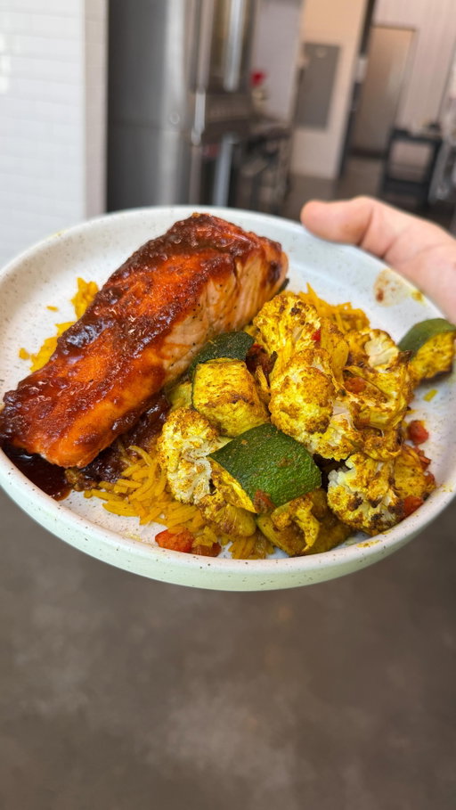 Something to elevate your week night menu. Wearing my new @hedleyandbennett apron 👀👀

Honey Harissa Salmon
• 4 salmon fillets (about 6 oz each)
Glaze
• 2 tbsp harissa paste
• 1 tbsp honey
• 1 tsp smoked paprika
• 1 tsp garlic powder
• ½ tsp cumin
• 1 tsp cornstarch
• 2 tbsp water
Season the salmon with salt and sear in a hot pan with a little oil for 2 minutes per side. Transfer to a 400°F oven for 5-7 minutes.
While the salmon rests, add all of the glaze ingredients to the same pan and simmer for 1-2 minutes until thick and glossy. Spoon over the salmon.
Turmeric Rice
• 1 cup basmati rice
• 1¾ cups chicken stock
• ¼ white onion, finely diced
• 1 tsp turmeric
• ½ tsp cumin
• 1 tsp garlic powder
• 1 tsp kosher salt
Rinse the rice, then combine everything in a pot. Bring to a boil, cover, reduce to low, and cook for 15 minutes. Let it rest for 10 minutes before fluffing.
Moroccan Vegetables
• 1 zucchini, diced
• 1 small head cauliflower, cut into florets
• ¼ bell pepper, diced
• 1 tbsp olive oil
• 1 tsp turmeric
• 1 tsp cinnamon
• 1 tsp cumin
• 1 tsp kosher salt
Toss everything together and roast at 400°F for 13-14 minutes.
Finish everything with a squeeze of fresh lemon and some chopped parsley or cilantro if you have it.