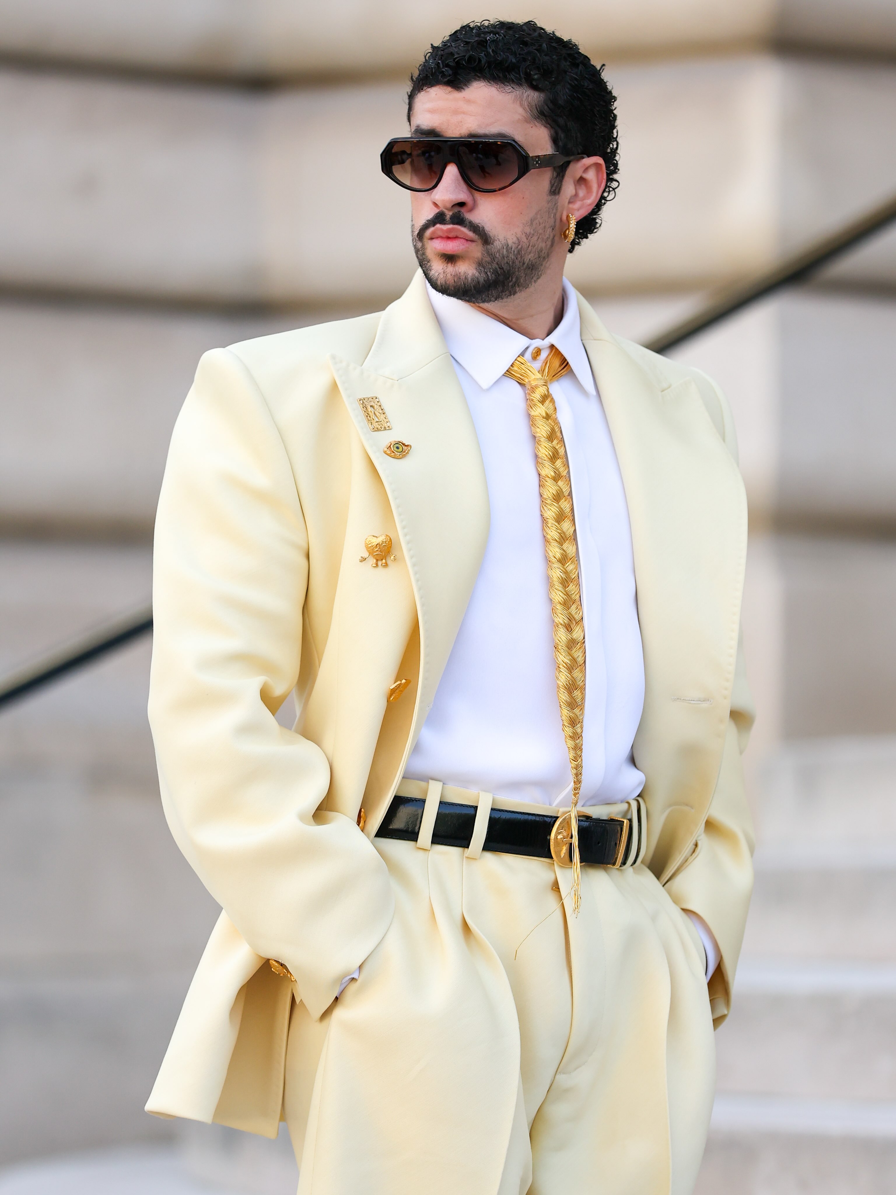 Tití me preguntó if @badbunnypr could get more fine and I said the limit does not exist. Benito has touched down in Paris for the @schiaparelli Haute Couture show, making a strong case for a braided hair tie and a butter yellow suit. Oui 🤌