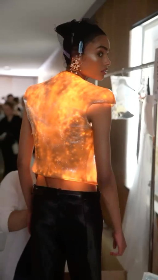 EVERYTHING IS ILLUMINATED 

ANA BEATRIZ - LOOK 12 
SCHIAPARELLI HAUTE COUTURE FALL/WINTER 2026-2027 BY @DANIELROSEBERRY. 

Glowing sharp-shouldered tailored jacket in an amber hue silicone inspired by the Maison’s iconic Shocking perfume bottle. The jacket is embroidered with the signature Measuring Tape along the edge and illuminated from within. Low-rise bias-cut pants in black liquid satin. Gold plated brass chandelier necklace adorned with rhinestones and baroque pearls. Anemone inspired earrings in gold brass and rhinestones. Black brushed leather belt embellished with a buckle inspired by a coral reef. Black satin sandals with a curved heel, a rhinestone bijou and mirror leather soles.

Video: @christophe_tiphaine 
Music: @benbrunnemer 

#Schiaparelli