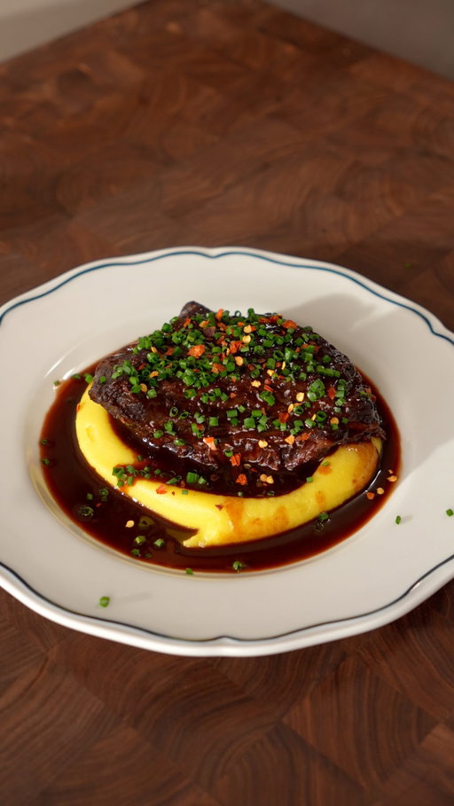 Braised Beef Cheeks 🥴

Ingredients

Braised Beef Cheeks:
- 4 beef cheeks
- 1 bottle red wine
- High smoke point oil (to sear the cheeks)
- Plain flour seasoned with salt and pepper
- 2 onions
- 2 medium carrots
- 3 celery ribs
- 4 cloves garlic
- 2 tbsp tomato paste
- 6 cups beef stock
- 1 bay leaves
- 1 sprig thyme & rosemary
- 1 tsp dijon mustard
- Salt and pepper

Mashed Potatoes (Pomme purée):
- 6 medium Yukon potatoes
- 200–250g unsalted butter
- 1 cup whole milk (or cream)
- 1–2 tsp salt, to taste

Braised Beef Cheeks:
- Coat the beef cheeks in seasoned flour. Heat a little oil in a pot over medium heat and sear the beef until browned on all sides. Remove and set aside.
- In the same pot, cook the onion, carrot, celery, and garlic for about 5 minutes. Add the tomato paste and cook for another 2–3 minutes.
- Pour in the red wine and simmer until reduced by half. Add the beef stock, thyme, rosemary, bay leaf, salt, and pepper.
- Return the beef cheeks to the pot. Cover with a cartouche and a lid, then cook on low heat for 4 hours. (I recommend cooking in a **285°F / 140°C oven** for 4 hours.)
- Remove the beef cheeks and strain the cooking liquid into a saucepan. Reduce until slightly thickened, then whisk in the butter and Dijon mustard to finish the sauce.

Mashed Potatoes (Pomme Purée):
- Place the potatoes in a pot of cold water. Bring to a boil and cook for about 40 minutes, or until tender.
- Peel the potatoes while they’re still warm and pass them through a potato ricer.
- Return the potatoes to a saucepan over low heat. Gradually fold in the butter until fully combined.
- Pass the potatoes through a fine sieve, then stir in the milk until smooth. Season with salt to taste.