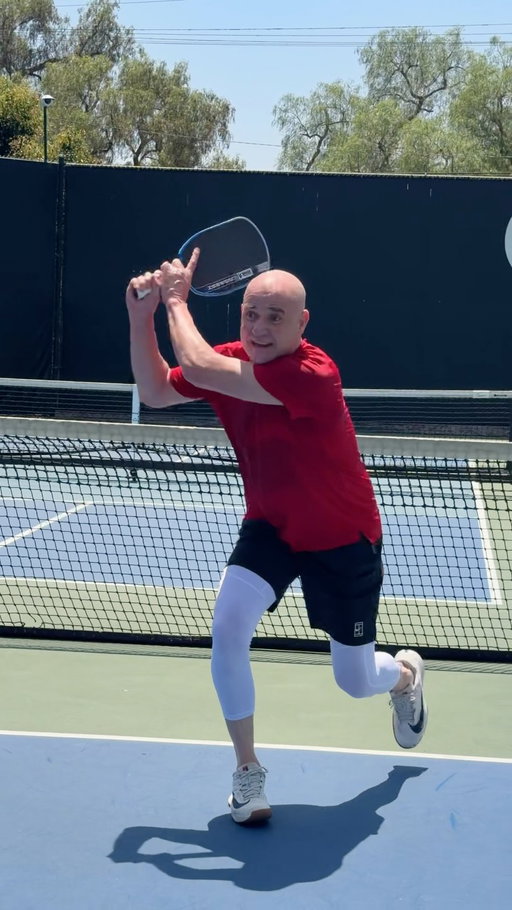 I love when @agassi says that his two-handed backhand paid for a lot of things in his life. When seeing it in person, the mechanics don’t change on a pickleball court. The fundamentals still apply.

Look at what makes his two-handed backhand so lethal:

-Pre-Planned Direction: In this drill, we were only going cross-court. Notice the early paddle preparation. The decision to go cross-court is made before he swings, which is why that contact point is way out in front.

-Footwork & Torque: Watch his outside leg pull around after contact to release the rotational torque, making this exact stroke repeatable every single time. The shot naturally brings that left leg around which also allows Andre to push off and recover for the next ball. 

-Still Head: Notice how Andre’s head is stable through contact. Eyes are locked on the ball. His head doesn’t pop up which means his body doesn’t either. Zero wasted movement. 

Proof that elite mechanics translate anywhere.

Which part of his setup are you stealing for your own game?

🎥: @ccgsocial