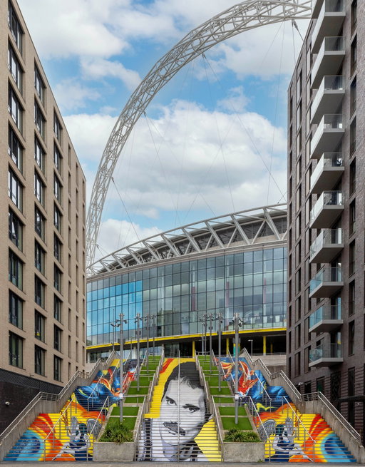 Freddie is back at Wembley. 💛

‘I’m Mr. Mercury’ has arrived on Wembley Park’s Spanish Steps, ahead of what would have been Freddie Mercury’s 80th birthday this Saturday.

Wembley was one of Freddie’s great stages. With Queen, he made rock history here at Live Aid in 1985, before returning for two sold-out @wembleystadium shows in 1986. By then, Queen had already played Wembley Arena, now @ovoarena , 10 times from 1978.

For this tribute, Wembley Park has joined forces once again with Frank Styles (@faostyles), whose ‘Auras’ tribute to Taylor Swift became a global sensation in 2024.

Look closely and you’ll find koi carps, a nod to Freddie’s love of Japan, and fairies representing his Virgo star sign, the same symbol he incorporated into the @officialqueenmusic crest he designed himself.

The portrait only works from one spot. Stand on the yellow marker, 65ft back, and Freddie snaps into place. Move away, and the image scatters again.

Take your time on the way up. Across all 58 steps are lyrics from songs Freddie wrote, alongside his own words from beyond the stage. Together, they tell something of both the private man and the artist the world knew.

We are immensely grateful to the @freddiemercury Estate, led by Freddie’s long-time manager Jim Beach, for the extraordinary generosity with which they opened Freddie’s archive to us, shared material from his life and entrusted us with his portrait for the heart of this tribute.

‘I’m Mr. Mercury’ is free for everyone to see, 24 hours a day, until December 2026.

Only at Wembley Park.

Full story at the link in bio.

Swipe for more photos and details. 👉

Images: Chris Winter / Wembley Park

Frank Styles painted I’m Mr. Mercury as four separate works, then composed them into a single anamorphic image applied across all 58 Spanish Steps.

The mural is 30ft tall, but it only exists from one place: a yellow circle marked on the ground opposite the Steps. 

Stand there and the fragments lock into Freddie Mercury’s face. Move a few paces in any direction and it breaks back into colour and line.

A symmetrical abstract across the steps features koi carp to represent Freddie’s life-long love of Japan and are a nod to his
