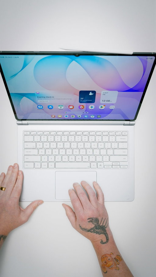 The tablet has a 14.6-inch Dynamic AMOLED 2X display with 120Hz, HDR10+, and 1,600 nits peak brightness. Inside is the 3nm MediaTek Dimensity 9500, which Samsung rates at 19% faster CPU and 61% faster AI than the Tab S11 Ultra. You get 12GB RAM, storage up to 1TB with microSD, and an 11,600mAh battery with 45W fast charging. It’s still 5.1mm thin and 692g, and now IP68 with 4-channel spatial audio.

On the software side, it runs Android 17 with One UI 9 and gets seven OS upgrades. Galaxy AI now includes Note Assist summaries and three-way Multi Window, and Adobe Photoshop comes preloaded, a first for an Android tablet. The S Pen is included.

The Pro Keyboard has an aluminum build, backlit keys with 1.0mm travel, a large trackpad, and a hinge with a kickstand. Its Galaxy AI Key launches Gemini, Bixby, or Perplexity. This is the Samsung DeX laptop-replacement setup.

The Galaxy Tab S12 Ultra starts at $1,399.99 and is available October 7 in Gray and Silver.