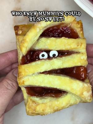 Flaky, fruity, and frightfully adorable, these cherry mummy hand pies will be your new favorite Halloween treat! Cut puff pastry into rectangles (I got three per sheet plus the strips for wrapping). Add your favorite filling, I used cherry, my hubby’s favorite, and leave a small border around the edge. Brush the edges with milk, layer on the strips in a fun mummy pattern, and trim any excess. Sprinkle with powdered sugar and bake at 350°F for 20–25 minutes until golden. Let cool, then finish with edible googly eyes. #halloweenbaking #cherrydessert #handpies #spookyfood #HalloweenTreats 