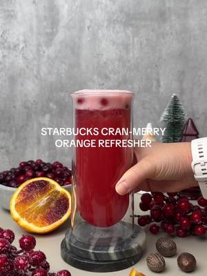 STARBUCKS CRAN-MERRY ORANGE REFRESHER🎄 Sadly, Starbucks didn’t bring it back this year (cue collective heartbreak 💔). But don’t worry, I’ve got you covered. This homemade version tastes bright, citrusy, and perfectly spiced, just like the OG, and you can make it at home any time of year for a fraction of the cost🫶🏽 Ingredients: Cranberry Orange Base: 3.5 cups fresh cranberries 3 cups cranberry juice 3 cups blood orange juice or regular orange juice 1/2 cup granulated sugar 2-3 whole cloves or 1/8 teaspoon ground cloves 1/4 teaspoon ground/grated nutmeg 1 teaspoon green coffee bean powder, optional Starbucks Cran-Merry Orange Refresher: 1/4 cup fresh cranberries, or freeze-dried 6 ounces water or lemonade, or coconut milk 6 ounces Cranberry Orange Base Ice Instructions: In a large pot, add cranberries, cranberry juice, blood orange juice, water, sugar, cloves, nutmeg, and (optional) green coffee bean powder. Stir to combine. Heat over medium until it begins to bubble. The cranberries may pop — totally normal! Reduce heat to medium low and simmer for 10 minutes, stirring occasionally. Carefully pour the mixture through a fine mesh strainer into a heat-safe container, removing the solids and spices. Let cool for 1 hour at room temperature, then seal and refrigerate for up to 2 weeks. For the Cran-Merry Refresher: Combine the Cran-Merry Orange Base and water (or lemonade or coconut milk) to a cocktail shaker or mason jar. Add ice and a small handful of fresh or freeze-dried cranberries. Shake until chilled, then pour into a glass and enjoy!🎄🎉🎁 Follow for more at home Starbucks recipes! #cranmerryrefresher #cranmerry #starbuckscranmerry #cranmerrydrink 