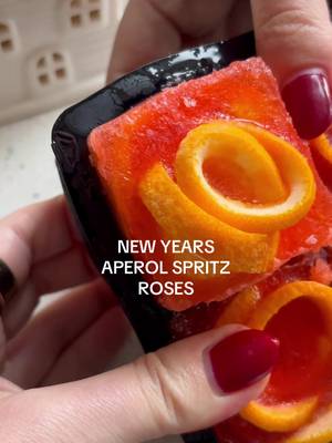 New Years Aperol Spritz Frozen Roses 🍊🌹 Because New Years Eve is only 3 days away!! These are a spin off my Orange Rose Mimosa Cubes and are soooo perfect for celebrating! INGREDIENTS - 8oz Aperol 4oz club soda 2 oranges  Bottle of Prosecco DIRECTIONS -  1) Slice your oranges thinly, then cut each slice in half to make semicircles. This will allow them to be easily folded into rose shapes. 2) Take 3-4 half-slices and fold them into the mold, layering them so they resemble the petals of a rose. Adjust the pieces as needed to achieve the rose look. 3) Combine the Aperol and soda into a glass. Then pour into each mold, filling to just below the top. The Aperol mixture will freeze around the orange slices, holding them in place and enhancing the flavor. 4) Place the tray in the freezer for at least 4-5 hours or until completely solid. For best results, freeze overnight. 5) Pop out the Aperol Spritz Frozen Roses and add them to a glass of bubbly to create a gorgeous, citrus-infused mimosa! #holidaycocktail #aperolspritz #aperoldrink #holidaydrink #proseccodrink 