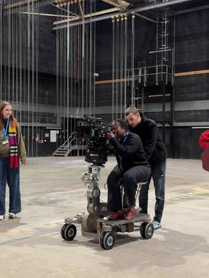 POV: This is what being a trainee sounds like… 🎥 One of our Accounts Trainees, Anne, shows us around a camera workshop as part of the Trainee Programme! Alt text: A group of taking it in turns to sit on a camera dolly whilst, learning how to be a Camera Operator.