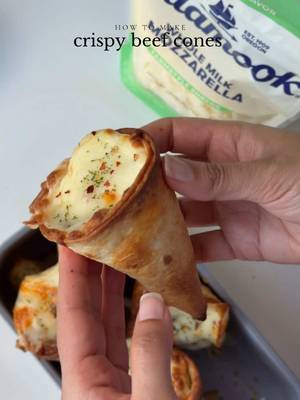 Game day snacks don’t have to be boring 🏈 These Crispy Beef Cones are stuffed with spiced beef and finished with creamy, melty @Tillamook Whole Milk Mozzarella #TillamookPartner Ingredients For the beef mixture: 1 lb. ground beef, 80% lean 20% fat 1 small yellow onion, finely chopped 1 tbsp fresh garlic, minced  4 tbsp tomato paste Salt to taste 1 tsp black pepper  1 tsp garlic powder  1 tsp smoked paprika powder  1/2 tsp red chili powder  1 tsp red chili flakes 1 cup water 1 cup mixed bell peppers, diced 1-2 Serrano peppers  2 tbsp oil To assemble: 8 medium tortillas, halved 8oz Tillamook Farmstyle Mozzarella Shredded Cheese 1 tsp dried parsley for garnish  Cooking spray  Toothpicks Instructions: In a pan, heat oil on medium heat. Once the oil is hot, add chopped onions and garlic. Sauté for 1 to 2 minutes until the onions become translucent. Then, add and sauté the beef for 2 to 3 minutes until it changes color. Add salt, pepper powder, red chili powder, garlic powder, and red chili flakes. Mix well and cook for 1 to 2 minutes until the spices are well combined.  Add the tomato paste and stir until it’s fully incorporated. Then, add the water. Cover the pan and stir occasionally until the mixture thickens. This should take about 10 to 12 minutes. Once the water has mostly evaporated and the beef is cooked, add the bell peppers and Serrano peppers cook for 3 to 4 minutes. Remove the pan from heat and set it aside. Preheat the oven to 400°F and line a baking sheet with parchment paper. Shape each tortilla half into a cone and secure the seam with a toothpick. Lightly spray the outside of each cone with cooking spray. Place cones seam-side down on the baking sheet. Bake empty cones for 8-10 min until golden and crisp. Fill each cone with the beef filling and cheese. Stand each filled cone upright in a loaf pan, bake the cones for 8 to 10 minutes or until the cheese is melted and bubbly. Garnish with parsley and serve warm. #beefcones #crispycones#Recipe 