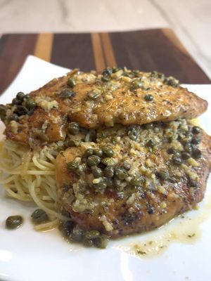 Chicken Piccata with that silky lemon butter caper sauce spooned all over pasta. One bite and suddenly you feel like you trained in a little Italian kitchen somewhere. This one is staying in the weeknight rotation for sure. 🤌🏾🤌🏾🤤 Chicken Piccata  Ingredients 2 large chicken breasts, butterflied 1 cup flour 1 tsp garlic powder 1 minced shallot 5 cloves garlic, minced 1/4 cup olive oil 1/2 cup white wine 1/2 cup chicken stock Juice of 1/2 lemon 2 tbsp capers 2 tbsp minced parsley 1 tsp diced tarragon 3 tbsp cold butter, cubed Parmigiano Reggiano, for finishing Salt and pepper to taste Cooked spaghetti Instructions Pound chicken thin and season with salt and pepper. Season flour with salt, pepper, and garlic powder, then lightly dredge the chicken. Heat olive oil in a skillet and cook chicken until golden and cooked through. Remove and set aside. In the same pan sauté shallot and garlic, then deglaze with white wine and reduce slightly. Add chicken stock, lemon juice, and capers and let simmer. Stir in parsley, tarragon, and cold butter to create a silky sauce. Return chicken to the pan and spoon sauce over to finish cooking. Reserve some of the pan sauce for the pasta. In a separate skillet, add the cooked spaghetti with the reserved sauce and Parmigiano Reggiano. Toss until glossy and coated, adding a splash of stock if needed to loosen the sauce. Serve the chicken over the pasta and spoon extra sauce on top.   #chicken #italianfood #food #EasyRecipes #yum