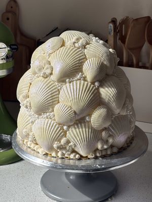 A white chocolate seashell cake 🐚✨ Layered with blueberry whipped cream and a vanilla Swiss meringue buttercream.. recipe is on my substack!