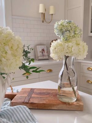 My simple hack to revive wilted hydrangeas ✨  Hydrangeas are one of my absolute favourite flowers BUT they wilt SO easily... Here's my little hack to bring your wilted hydrangeas back to life! Materials You Will Need: - Wilted hydrangeas - Hot water (almost boiling) - Vase - Sharp knife - Cutting board Directions: 1. Bring a kettle or pot of water to a boil. Pour the water into a tempered glass vase or bottle (so it doesn't crack). It doesn't need to be full, just enough to cover a few inches of the stem. 2. Place the hydrangeas on the cutting board and use the sharp knife to cut the end of the hydrangea at a 45 degree angle. Then cut a small slit vertically up the middle of the newly trimmed stem. 3. Place the hydrangeas in the vase filled with hot water. 4. Let sit for a minimum of one hour and voila! Revived hydrangeas. I will sometimes repeat this process if they are badly wilted. #hydrangea #hydrangeahack #wiltedflowers #howtorevivehydrangeas #gardening #fraicheliving