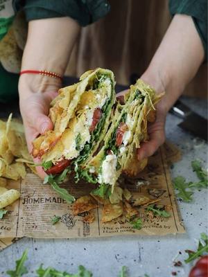 #AD I partnered with @flvr global to make the crispiest, crunchiest wrap using one of my favorite salads: a Caprese Salad & Lay’s Wrap! The Lay’s add the perfect texture to the cheesy homemade wrap and paired with fresh caprese fillings, makes for the most delicious and simple lunch or dinner.   #FLVR #Lays #partnership #LaysRecipe Cheesy Caprese Salad & Lay’s Wrap Ingredients: For the Wrap: ½ cup mozzarella cheese ¼ cup parmesan cheese 1 cup Lay’s Sour Cream & Onion chips For the Filling: ¼ cup basil pesto Sliced heirloom tomato Fresh arugula 1 burrata cheese ball Olive oil Balsamic vinegar Additional Lay’s chips Instructions: Prepare the Wrap: Preheat the oven to 350F. On a parchment-lined baking tray, add mozzarella cheese and parmesan cheese in a rectangle shape in an even layer. Top with Lay’s chips and bake until the cheese is melted and brown on the bottom and edges. Remove from the oven and let rest for 5-10 minutes until the cheese is set. Assemble the Wrap: Remove the wrap from the tray and place on a plate. Top with pesto, sliced tomato, and arugula. Tear the burrata cheese on top, then add a drizzle of olive oil and balsamic vinegar. Top with additional Lay’s chips. Roll up the wrap carefully and serve immediately. Bon appetit!