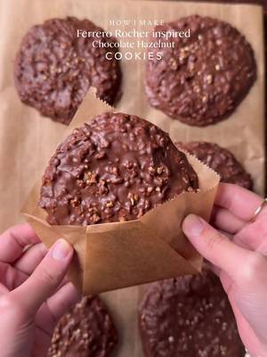 Ferrero Rocher inspired chocolate hazelnut cookies🤤. Ferrero Rocher vibes in every bite, Rich chocolate, crunchy hazelnuts, and that melt-in-your-mouth magic. INGREDIENTS: •115g cold chopped unsalted butter •80g caster sugar •80g light brown sugar •238g plain flour  •½ tsp salt •1 & ½ tsp baking powder •¼ tsp baking soda •1 whole egg + egg yolk  •½ tsp vanilla •250g Cooking or Milk chocolate  •1/2 cup Chopped and roasted hazelnuts  •Nutella and hazelnut spread  INSTRUCTIONS: •Cut cling wrap into small squares. Scoop ½ teaspoon Nutella and Scoop ½ teaspoon of Hazelnut spread onto individual cling-wrap squares. Fold to seal and freeze until solid. (Repeat for however many stuffed cookies you plan to make.) •In a large mixing bowl, add the cubed butter and whisk until slightly creamy. Add the white sugar and light brown sugar, then whisk together until well combined and fluffy. •Add the eggs, vanilla extract. Whisk until fully incorporated. •Add the flour, baking powder, baking soda, and salt. Gently mix until just combined, do not overmix. •Portion the dough into 65g-70g balls. Press a frozen Nutella hazelnut piece into the centre of each dough ball, seal well, and roll into a smooth ball. •Place the cookie dough balls onto a tray and freeze for at least 1 hour (or overnight for best results). •Preheat oven to 175-180C (350°F). Bake for 10-15 minutes or until the tops are lightly golden while the centres remain soft. •Remove from the oven and let cool. •Melt the cooking or milk chocolate using double broiler method and add chopped & roasted hazelnuts in it.  •Spread a layer of melted chocolate–hazelnut mixture onto baking paper, just enough to coat the base of the cookie. Gently place the cooled cookie on top, then spoon more of the mixture over it, making sure the cookie is fully covered and evenly coated. •Let the chocolate mixture set completely before serving, Enjoy!  NOTE: Store any extra dough balls in an airtight container or freezer bag and freeze for later. Whenever a cookie craving hits, bake straight from frozen🫶🏻 #ferrerorocher #cookie #fyp #explorepage✨ #chocolate 