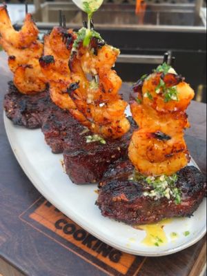 Hot Honey Steak and Shrimp Recipe 👇 Recipe: Servings: 4-6 People Prep: 15 minutes Cook: 1 hour Cure: 1 day Steak and Shrimp: 3-4 Filet Mignons 1.5 lbs Shrimp, peeled & de-veined 2 tbsp Kosher Salt 2 tbsp Favorite Steak Rub 2 tbsp Favorite Seafood Rub Cure: 1 Gallon Honey ½ cup Red Chili Flakes Instructions: Cure: Season your steaks generously with kosher salt. Gently heat up your honey until it is very viscous. Add your steak to a food safe container. Cover in the honey, cover the container and place in the fridge for 24 hours to cure. If the honey does not cover the steak completely, flip the steak every 2 days. About 1 hour before cooking, repeat heating up the honey. Add your shrimp to the honey and let sit in it until ready to cook. Steak: Pull the shrimp and steak out and wipe off any excess honey. Generously season with your favorite steak rub and your favorite seafood rub. Set to the side. Preheat your smoker to 250F for indirect cooking. Add your steak to cook for about 30 minutes until 120F internal. Pull off once done to rest for 10 minutes. Heat up a high heat fire (around 400F) and place the steak over the fire for 1 minute per side to get a good crust. Heat up a cast iron skillet with some oil. Add the shrimp to the skillet to cook for 1-2 minutes until done. Pull everything off, serve with some butter, slice up the steak and enjoy!