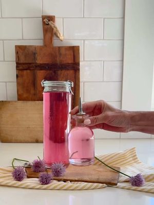 Here's how you make my French countryside inspired Chive Flower Vinegar... because this is the kind of DIY that makes you feel like the main character of your own European summer. 💜 You can drizzle it over EVERYTHING, gift it, or just stare at it lovingly on your counter (hi, c'est moi!) because you're going to be obsessed. Ingredients: 1 heaping cup of chive blossoms (rinsed and dried) 2 cups white wine vinegar or champagne vinegar  Instructions: 1. Harvest your blossoms when fully open. Rinse and pat them dry – any excess water can affect the flavour and preservation of your vinegar, so don't rush this step! 2. Fill the jar ¾ of the way with blossoms. 3. Pour the vinegar over the blossoms, ensuring they’re fully submerged. 4. Seal and let it infuse at room temperature for 1–2 weeks, shaking gently every few days. 5. Strain into a clean bottle and store in a cool, dark place or the fridge More info up on the blog! (Link in bio!) Save this to use up those beautiful blossoms, or when you need a gift that will literally have them squealing with delight! 🌸 #hostessgift #chives #DIY #homemade #vinegar
