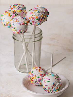 Because everything’s better with sprinkles 🎉🍰✨  RECIPE   Makes about 25 pops   Small batch confetti cake ¾ cup vanilla frosting ½ cup mixed sprinkles, plus more for topping 1 bag candy melts   Blend up the confetti cake until crumbly. Add the vanilla frosting and blend until the mixture easily sticks together. Add the sprinkles and mix to combine.   Use a cookie scoop to form cake balls, about the side of a ping pong ball. Melt the candy melts according to the package directions. Dip the tip of a lollipop stick into the melted coating and stick halfway into the cake balls (optional). Dip the cake balls into the coating, swirling and lightly shaking until evenly coated. Cover with more sprinkles and place upright in a cup or jar to dry. Reheat the coating as needed and repeat with the remaining pops.