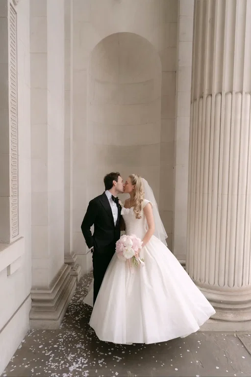 I decided when I was fifteen that I would marry JJ at the Old Marylebone Town Hall- we went to school together around the corner and passed it every day for years. Back then, I thought you had to choose between a church or a town hall, so I thought yes, this one is perfect! I can’t describe the surreal and magical feeling of having that teenage dream come true (he wasn’t even my boyfriend, so I was dreaming big!). I was late, of course. I was escorted from The Ritz in a London black cab by a close family friend who has known me since I was born. I said “Can you get us to the town hall in five minutes?”, and he said “I’ll get you there in three!”. I walked down the aisle to a string trio playing “Once upon a dream”, another detail I planned as a little girl. Our ceremony was simple, but brimming with emotion- even our wonderful registrar, who has performed hundreds of marriages, was brought to tears more than once! Placing a ring on the finger of my first and forever love, is an unforgettable feeling. Why do they suddenly become EVEN MORE handsome with a wedding ring on? Having our turn walking down those famous steps, with our beaming friends and family showering us in confetti, felt like something out of an old film. We also had a surprise visit from a chimney sweep- an age old lucky wedding tradition that my parents also had, and sent our guests on to the reception in a vintage bus, another element inspired by my parents’ wedding. It was perfect- exactly what we’d always imagined and more 🤍 photos by @EmilyJayneWeddings  #londonwedding #townhallwedding #oldmarylebonetownhall #firstlove #2026wedding 