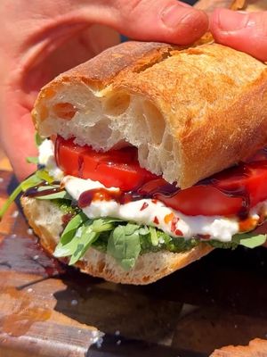 If I had to eat one sandwich all summer, it’d probably be this. A layer of fresh homemade pesto, arugula, burrata, heirloom tomatoes, red pepper flakes, flaky salt, extra-virgin olive oil, and a drizzle of balsamic glaze. #caprese #capresesandwich #beachvibes #summerrecipes  Caprese sandwich Easy sandwich recipe Beach sandwich  Burrata sandwich 