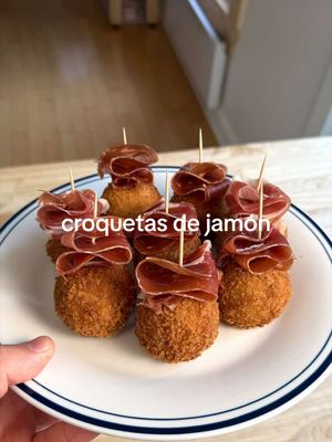 SPANISH CLASSICS 🇪🇸 ep. 1 - Croquetas de Jamòn  FULL RECIPE BELOW ⬇️  INGREDIENTS: 150g Serrano ham trims  150g country ham trims  150g sliced Serrano ham (optional) 1/ large onion 2 large cloves garlic 4 cups whole-fat milk 1/4 cup olive oil 1/4 cup butter 1/2 cup AP flour + more for dredging 227g (1 box) panko breadcrumbs 4 large eggs 1L canola oil  Fine salt (to taste) Ground white pepper (to taste) INSTRUCTIONS: INSTRUCTIONS: 1. Finely chop your Serrano and country ham trims. As mentioned in the video - you can also use other leftover cooked or cured proteins instead of ham. Peel & finely chop your onion.  2. Heat a large, heavy-bottom pan over medium heat. Add your olive oil and butter. Add your onion, and sauté for 1 minute, or until translucent. Peel, and grate your garlic cloves directly into the pot. Sauté for another 30 seconds. Add your diced ham. Sauté for 1-2 minutes. Sprinkle your flour around the pot. Stir to distribute the flour, and cook for another minute or so. Slowly start adding in your milk, 1 cup at a time, waiting until the milk has thickened before adding more. Once all your milk has been added, continue cooking down your bechamel, stirring often, until the mix has thickened.  You are looking for your bechamel to be quite thick (see video for reference), so it is not too liquid when shaped into a croqueta! Season your mix to taste with salt and white pepper.  3. Line a small tray with parchment paper, and spread out your Croquetas mix on the tray. This will allow the mix to cool faster, and help portion the croquetas later on. Transfer the mix to the fridge for at least 3-4 hours, or to the freezer for 60-90 minutes.  4. When ready to portion, invert your croqueta mix onto another large sheet of parchment paper. Portion it into 16 equal pieces. Working quickly, roll your croquetas into small balls between your palms, about the size of a golf ball. Place each croqueta back onto a new tray lined with parchment paper. For best results, transfer the tray to the freezer for 20-30 minutes to help set the croquetas, and make them easier to work with.  5. Prepare your breading set-up, with 3 separate trays of flour, beaten eggs, and panko. Dredge each croqueta first in the flour, then into the egg, then into the breadcrumbs. For best results, place each croqueta back into the egg mix, before giving it a second round of breading in the breadcrumbs. This will ensure the most even coating possible. Place all your finished croquetas back onto a tray lined with parchment paper, and once again, transfer them back into the freezer to set. If not serving same-day, keep your croquetas in the freezer until you are ready to serve them. You can fry them directly from frozen when you are ready. 6. Pre-heat your canola oil to 350 degrees Fahrenheit in a large heavy-bottom (or a deep fryer, if you have one). Fry your croquetas for 2-3 minutes, working in batches of 5-6, until the exterior is golden brown. You also want to ensure your croquetas have an internal temperature of 50-55 degrees Celsius. If frying from frozen, this might not be the case. If needed, finish your croquetas in the oven to ensure the filling has softened and warmed through.  7. Serve immediately with a small dollop of aioli, and a slice of fresh ham (optional), and enjoy! 