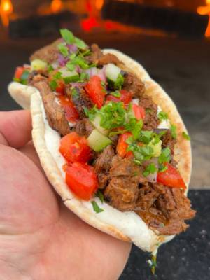 Beef Shawarma Recipe: Recipe: Servings: 4 People Prep: 15 minutes Cook: 1 hour Beef & Shawarma Seasoning: 2 Top Sirloin Steaks, sliced thin ½ cup Neutral Oil 1 tsp Ground Cumin 1 tsp Ground Coriander 1 tsp Paprika 3/4 tsp Ground Turmeric 1/2 tsp Ground Cloves 1/2 tsp Cayenne Pepper 1/2 tsp Ground Cinnamon 1-2 White Onions, cubed Shawarma Sauce: 1 cup Plain Yogurt 2 tbsp Tahini Sauce 1 tbsp Lemon Juice 1 tbsp Garlic Paste 1 tsp Cumin SPG, to taste Pita: 5-6 Large Pita Breads 1 cup diced Tomatoes ½ cup sliced Red Onion ¼ cup Chopped Parsley ¼ cup diced Cucumber Instructions: Slice thin your top sirloin steak (about ¼” in thickness). Pound flatter if needed Add the steak to a bowl along with seasoning and oil. Mix together thoroughly until well coated. Add to a trompo or skewer the steak. Stack on top of each steak until good. Add to the base some sliced onions and then set to the side. Preheat your oven to medium high heat (around 375F) for indirect cooking. Add the shawarma to the oven to cook for 1-1.5 hours until the beef is deep brown and cooked through. Pull off once done and let rest. In a bowl, mix together  the shawarma sauce. Carve off steak from the skewers and place on a warmed pita bread with sauce, tomatoes, red onion, parsley and cucumber. Serve and enjoy!