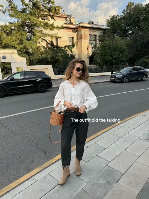 Effortless feminine outfit featuring a white linen shirt with voluminous sleeves, high-waisted black wide-leg jeans, a brown leather belt, beige suede ankle boots, a woven basket bag, pearl necklace, and statement sunglasses. A chic mix of relaxed European, feminine, and timeless style, perfect for summer to fall outfits, casual chic fashion, how to style a linen shirt, black jeans outfit, wide-leg jeans outfit, suede boots outfit, woven bag outfit, neutral capsule wardrobe, old money style, and effortless city looks. #parisianstyle #falloutfit #falloutfitinspo #scandistyle 