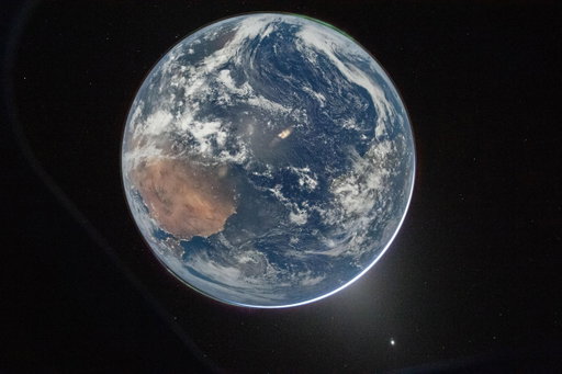 We see our home planet as a whole, lit up in spectacular blues and browns. A green aurora even lights up the atmosphere. That's us, together, watching as our astronauts make their journey to the Moon. 