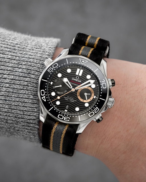 Rather than debuting alongside a new Bond film, OMEGA’s latest James Bond Seamaster arrives through the upcoming video game, 007 First Light.

Read more here: https://tinyurl.com/4djaf3bb

Created in collaboration with IO Interactive and Amazon MGM Studios, the new Seamaster Diver 300M Chronograph marks the first chronograph within Bond’s Diver 300M lineage, translating the watch used throughout the game directly into reality. The 44mm steel case is paired with a black ceramic bezel and wave dial, while touches of PVD bronze gold and red accents tie back to the visual language of the game.

Powered by the Co-Axial Master Chronometer Calibre 9900, the watch arrives on a new NATO strap that reworks the black, grey, and beige palette made famous by the No Time To Die Seamaster, now adapted specifically for the world of First Light.